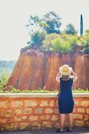 Tourists enjoying scenic view of red ochre cliff in Roussillon, Provence, France and taking photos....
