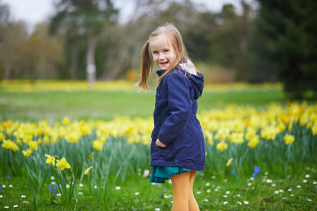 Adorable preschooler girl enjoying nice spring day in park during jonquils blooming season. Outdoor springtime activities for kids. Little child exploring natureの写真素材