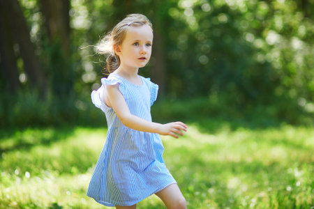 Happy cheerful preschool girl walking in park. Outdoors summer activities for kidsの写真素材