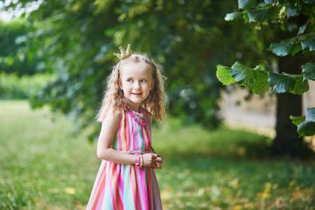 Cute preschooler girl in princess crown in park or forest on a summer day. Outdoor activities for childrenの写真素材