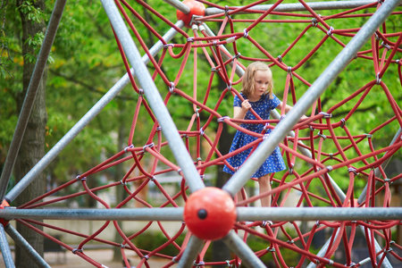 Adorable preschooler girl having fun in adventure park. Child on tree top net trampoline. Outdoor activities for small kidsの写真素材