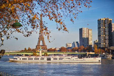 touristic boat floating near Eiffel tower and Grenelle bridge with Statue of Liberty on a bright fall day in Paris, Franceの写真素材