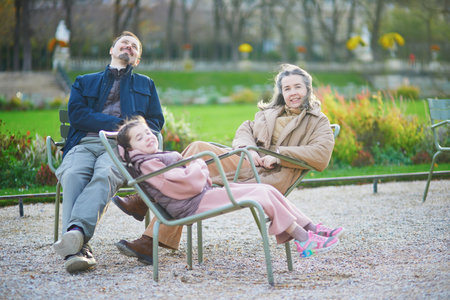 Happy family of three, father, mother and daughter enjoying family time together in Luxembourg garden of Paris, Franceの写真素材
