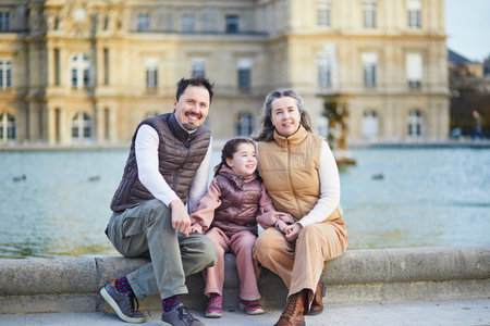 Happy family of three, father, mother and daughter enjoying family time together in Luxembourg garden of Paris, Franceの写真素材