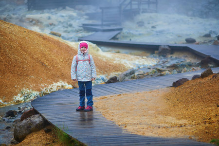 Adorable preschooler girl having fun in Krysuvik and Seltun geothermal area in Icelandの写真素材