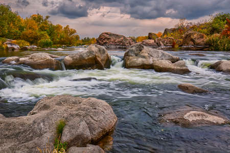Wild river landscape with huge rocks, overcast autumn scenery.