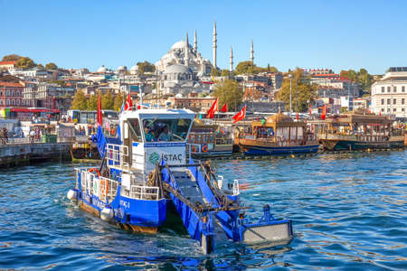ISTANBUL, TURKEY -  October 9th, 2019: View to Eminonu pier and Suleymaniye mosque across Bay of Golden Horn. Special ship cleans the water in the morningのeditorial素材