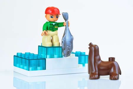 KHARKIV, UKRAINE - March 29th, 2020: Toy man feeding toy seal, plastic toys, pre-school education theme, isolated on whiteのeditorial素材