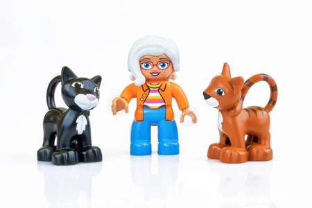 KHARKIV, UKRAINE - March 29th, 2020: Toy old lady with two toy cats, plastic toys, pre-school education theme, isolated on whiteのeditorial素材