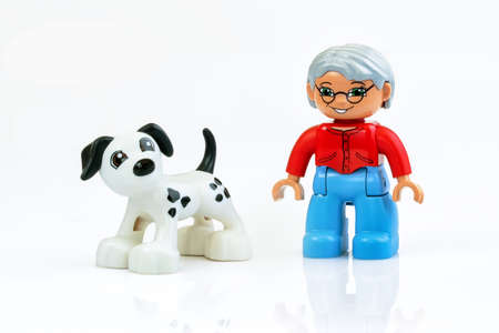 KHARKIV, UKRAINE - March 29th, 2020: Toy man walks toy dog, plastic toys, pre-school education theme, isolated on whiteのeditorial素材