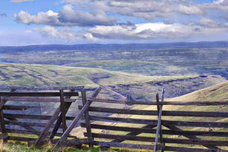Horizontal landscape of eastern Oregon south of Pilot Rock with an old wooden snow fence in the foreground and blue cloudy skies in the background.の写真素材