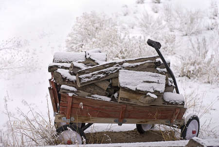 Wooden-sided red wagon loaded with firewood sits stranded in the snow after a snowstorm の写真素材