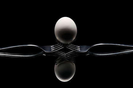 egg placed on forks on a dark backgroundの写真素材