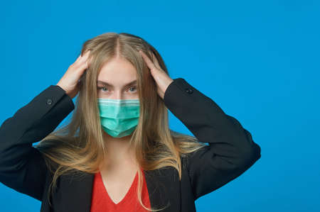 Business woman with a medical mask on her face holding her headの写真素材