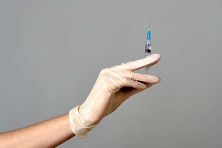 the hand of a medical glove holds a syringe with medicine, copy spaceの写真素材