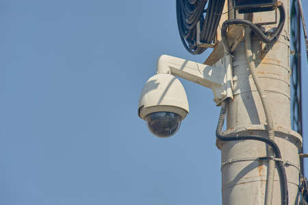 A surveillance surveillance camera is hanging on a poleの写真素材