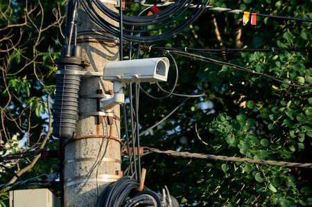 A security camera is hanging on a concrete postの写真素材