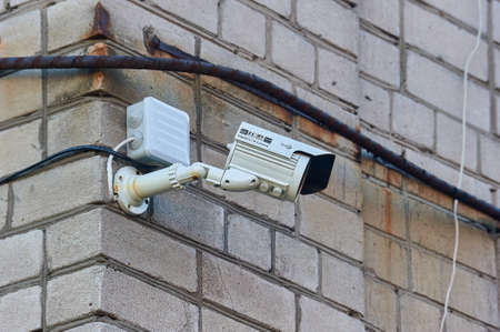 A surveillance camera is hanging on a brick wall
