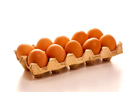 A dozen eggs on a cardboard stand on a white isolated background