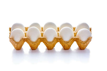 A dozen eggs on a cardboard stand on a white isolated background