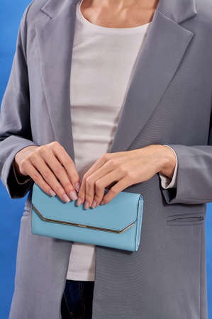 Blue purse close-up in the hands of women on a blue background