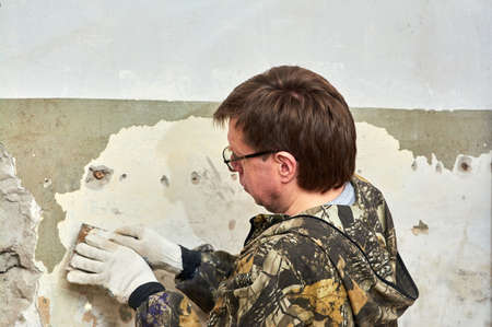 removing paint from the wall with a scraper, repairing the room