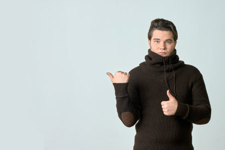 a man in a brown sweater and a bright color points to something and perfectly, showing an empty...