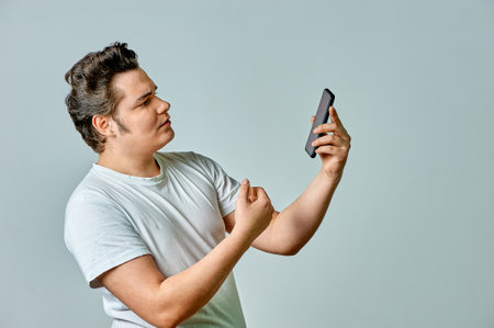 A man looks at the phone screen on a gray backgroundの写真素材