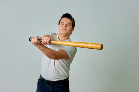 A man with a bat in his hands swings on a gray background