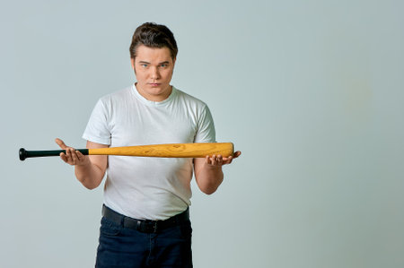 A man with a bat in his hands swings on a gray background