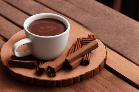 Cup of hot chocolate with cinnamon sticks on wooden table, closeupの素材