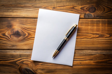 A pen sits on top of a piece of paper. The pen is black and the paper is white. Concept of simplicity and focus, as the pen and paper are the only objects in the sceneの素材