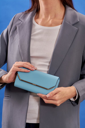 Womens hands hold a blue handbag