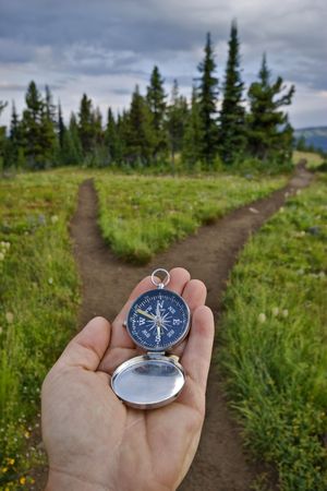 A compass is held out at a junction in the trail to check for direction.