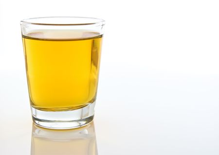 A close-up compsition of a shot glass filled with amber colored alcohol against a white backgroundの写真素材
