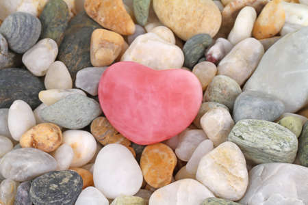 Beautiful roze quartz gem heart on pebbles