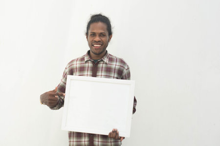 young black man pointing white board with isolated background in whiteの写真素材