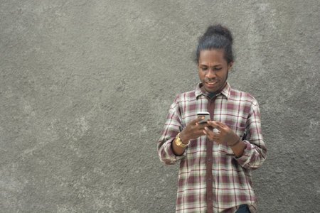 young bearded black man in casual dress using smartphone