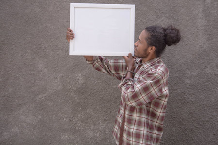 young bearded black man in casual dress holding white blank board