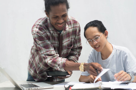 two friend with diffrent ethnic working together with laptop and tablet discussing something, two...