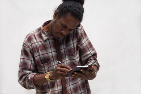 front view of black man taking notes while talking on phones, young papua man talk with smartphone...