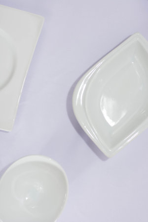 Flat lay of white plate, bowl, isolated in white or purple fabric, simple minimalist template...