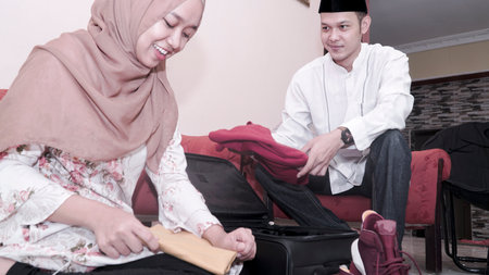 happy muslim couple man and woman put stuff in suitcase lugage prepare travelling for ramadan eid mubarak celebration -imageの写真素材