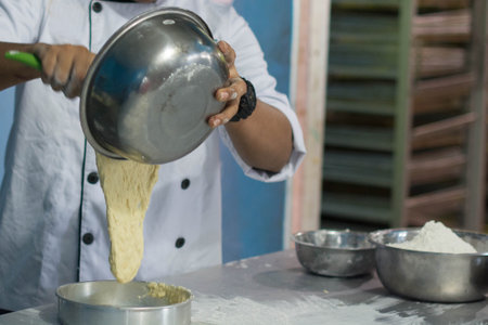 asian male baker, pastry chef prepare dough with flour inside bakery kitchen with oven
