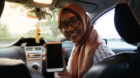 portrait of Asian Muslim hijab women facing the camera while driving a car