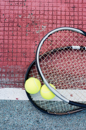 close up portrait of used tennis ball and racket on hard court