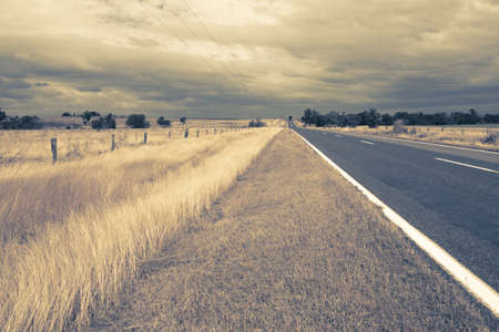 outback fields and road with wind in dry grassの写真素材