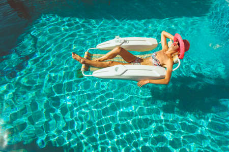 Young lady sunbathing in pool on a hot summers dayの写真素材
