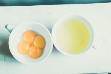 four eggs seperated into whites and yellows in two bowls
