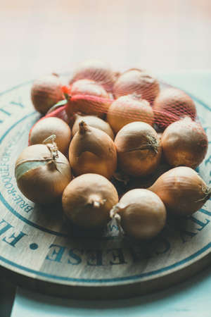 rustic looking bunch of brown onions sitting on a wooden lazy susanの写真素材
